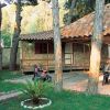 Una casa di pietra con patio coperto, persone sedute a un tavolo nel giardino.