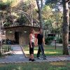 Due persone camminano su un sentiero tra alberi in un'area verde con case e una golf cart.