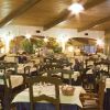 Un ristorante ampio con tavoli apparecchiati, sedie in legno e una luce calda dall'alto.