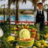 Un tavolo decorato con frutta intagliata, all'aperto vicino a una piscina.