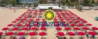 Spiaggia con ombrelloni rossi allineati e insegna Costaazzurra.
