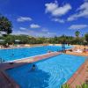 Grande piscina all'aperto con persone che nuotano e si rilassano sotto il cielo blu.