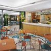Sala bar arredata con tavoli e sedie, bancone e bottiglie esposte.