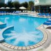 Ampia piscina all'aperto con area idromassaggio circolare e lettini blu.
