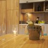 Bottiglia in secchiello su tavolo con bicchieri, cucina in legno sullo sfondo.