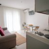 Soggiorno con divano beige, cucina e tavolo da pranzo.