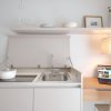 Cucina compatta con lavello, laptop e pentola bianca.