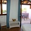 Camera con tende blu, finestra e porta aperta su un balcone con tavolo e sedie.