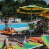 Persone rilassate in piscina con sdraio colorate.