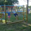 Tre ragazzi si divertono su una struttura di arrampicata in un parco.