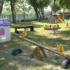 Parco giochi con altalene, scivoli e casetta giocattolo.