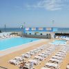 Piscina grande con lettini bianchi e vista mare.