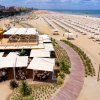 Spiaggia con stabilimento balneare, ombrelloni e sedie a sdraio.