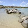Scogliera con mare cristallino e colline sullo sfondo.