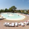 Piscina a forma libera con lettini bianchi, circondata da edifici colorati.