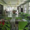 Sala da pranzo moderna con sedie verdi e grandi finestre.