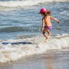Bambina salta tra le onde in spiaggia.