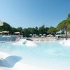 Grande piscina all'aperto con ombrelloni e alberi.
