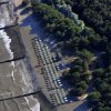 Veduta aerea di una spiaggia con ombrelloni blu e vegetazione costiera.