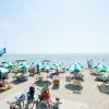 Spiaggia affollata con ombrelloni e sedie a sdraio.