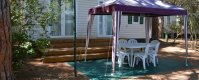 Un gazebo viola con tavolo e sedie bianche davanti a una casa mobile.
