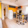 Cucina moderna con mobili gialli e grigi, e un tavolo nero.