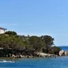 Casetta e nuotatori vicino a un mare blu e rocce.