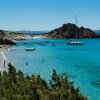 Un'isola con mare turchese e barche a vela.