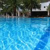 Una piscina blu circondata da sdraio e palme sullo sfondo.