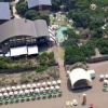 Vista aerea di una struttura sulla spiaggia con piscine e ombrelloni allineati sulla sabbia.