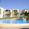 Piscina all'aperto con persone, circondata da edifici colorati con terrazze.