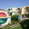 Un giardino con edificio colorato, sedie a sdraio e un cartello 