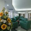 Sala d'attesa con divani verdi e fiori decorativi.