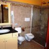 Bagno con lavandino nero, bidet, wc e doccia con piastrelle beige.