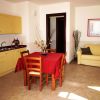 Cucina con tavolo rosso, sedie in legno, divano giallo e mobili gialli.