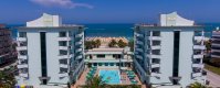 Due edifici alti con una piscina tra di loro e vista sul mare.