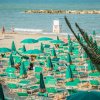 Spiaggia con ombrelloni verdi e mare azzurro.