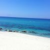 Spiaggia sabbiosa con acqua cristallina e rocce.