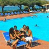 Persone rilassate su lettini accanto alla piscina.