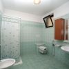 Bagno con piastrelle verdi, doccia con tenda, lavandino e WC.