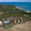 Veduta aerea di un complesso residenziale con piscina, campi e spiaggia nelle vicinanze.