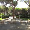 Tavoli e sedie in un giardino ombreggiato da alberi.