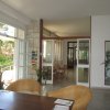 Sala luminosa con tavolo e poltrone, vista su porte aperte verso l'esterno.