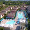 Vista aerea di un villaggio con piscine e ombrelloni.