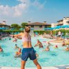 Persone fanno acquagym in piscina sotto un cielo sereno.