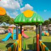Parco giochi colorato con scivoli e strutture verdi.