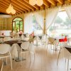 Sala ristorante luminosa con tavoli apparecchiati e tende bianche.