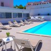 Piscina con sdraio beige e tavolini bianchi.