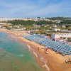 Spiaggia con ombrelloni blu e mare.