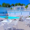 Piscina con lettini e tavolini bianchi.